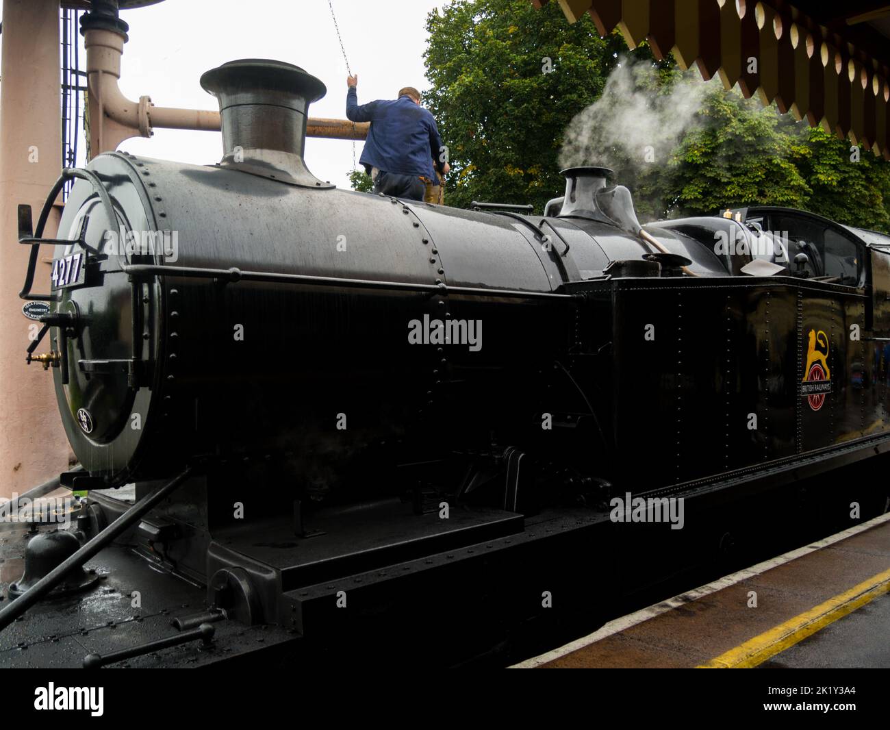 Driver filling steam engine No 4277 of Dartmouth Steam Railway with water in Paignton railway station Devon England UK before journey to Dartmouth Stock Photo