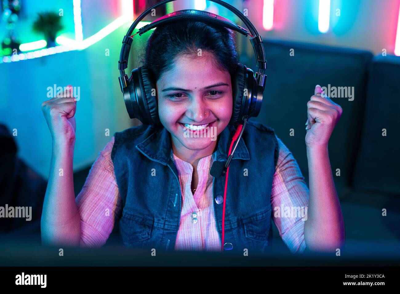top view of Excited gamer with headphones celebrating win by shouting while playing video game on computer at home - concept of entertainment Stock Photo