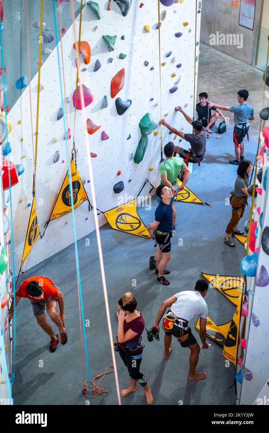 Rock climbing enthusiasts climbing the indoor rock-climbing wall in the Excelsior Shopping Centre, Civic District Singapore Stock Photo
