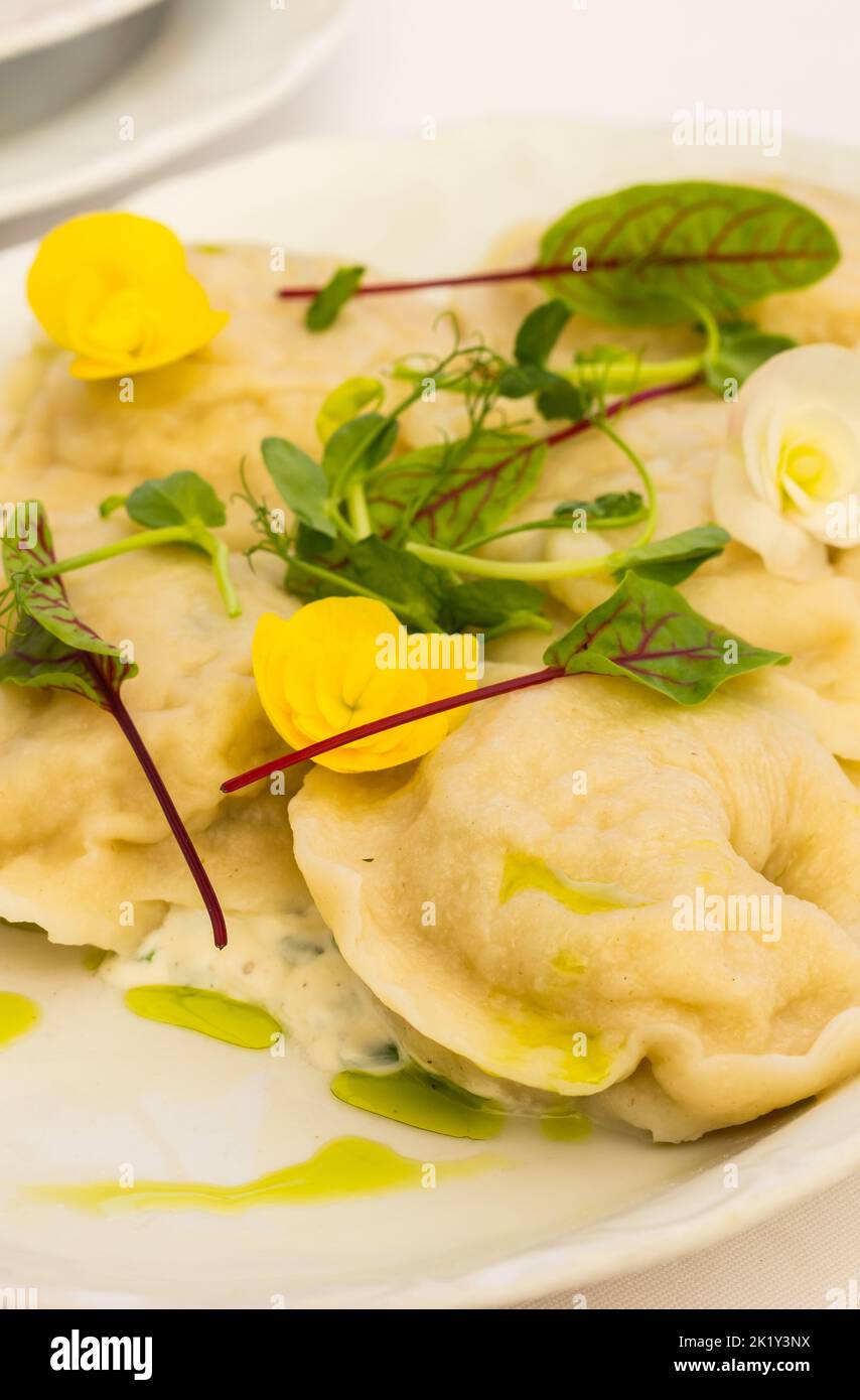 Traditional boiled Polish meat dumplings, served with sour cream and decorated with yellow flowers Stock Photo