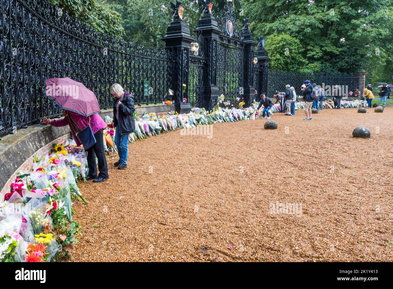 People start to lay flowers in the rain at the Norwich Gates to Sandringham House on the day following the death of Queen Elizabeth II. Stock Photo