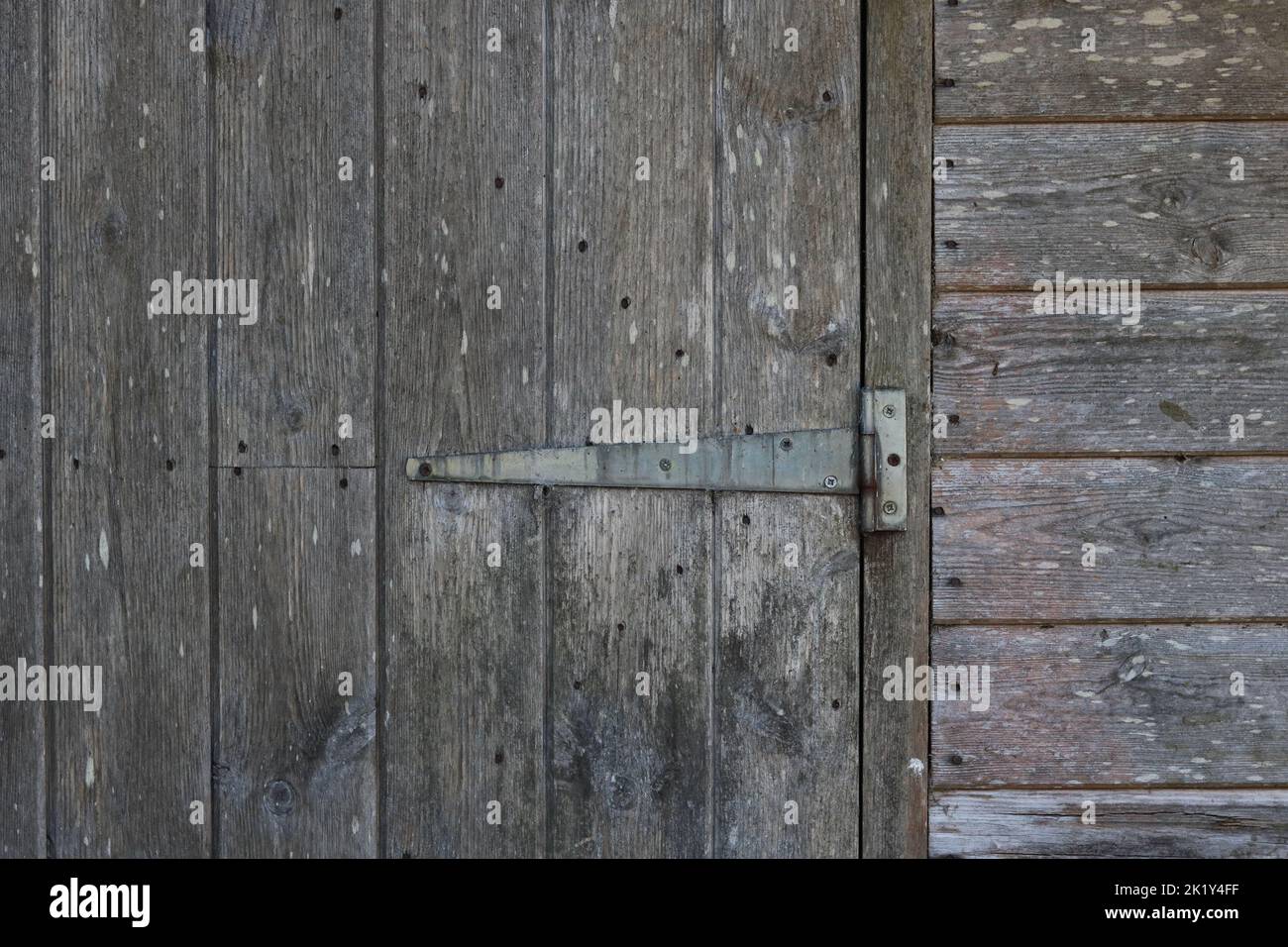 Exterior of old weathered wooden shed showing door and hinge detail Stock Photo