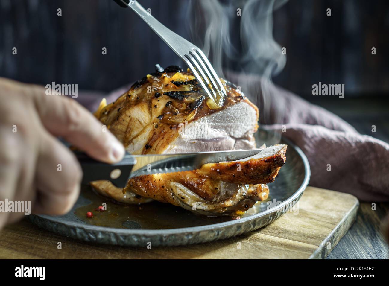 Slicing hot roasted pork with steam closeup. Low shallow focus Stock Photo