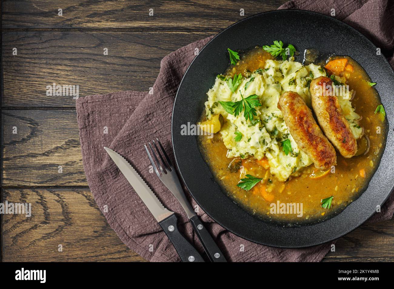Dutch stamppot of potatoes, kale and sausages with gravy on plate, top view with copy space Stock Photo