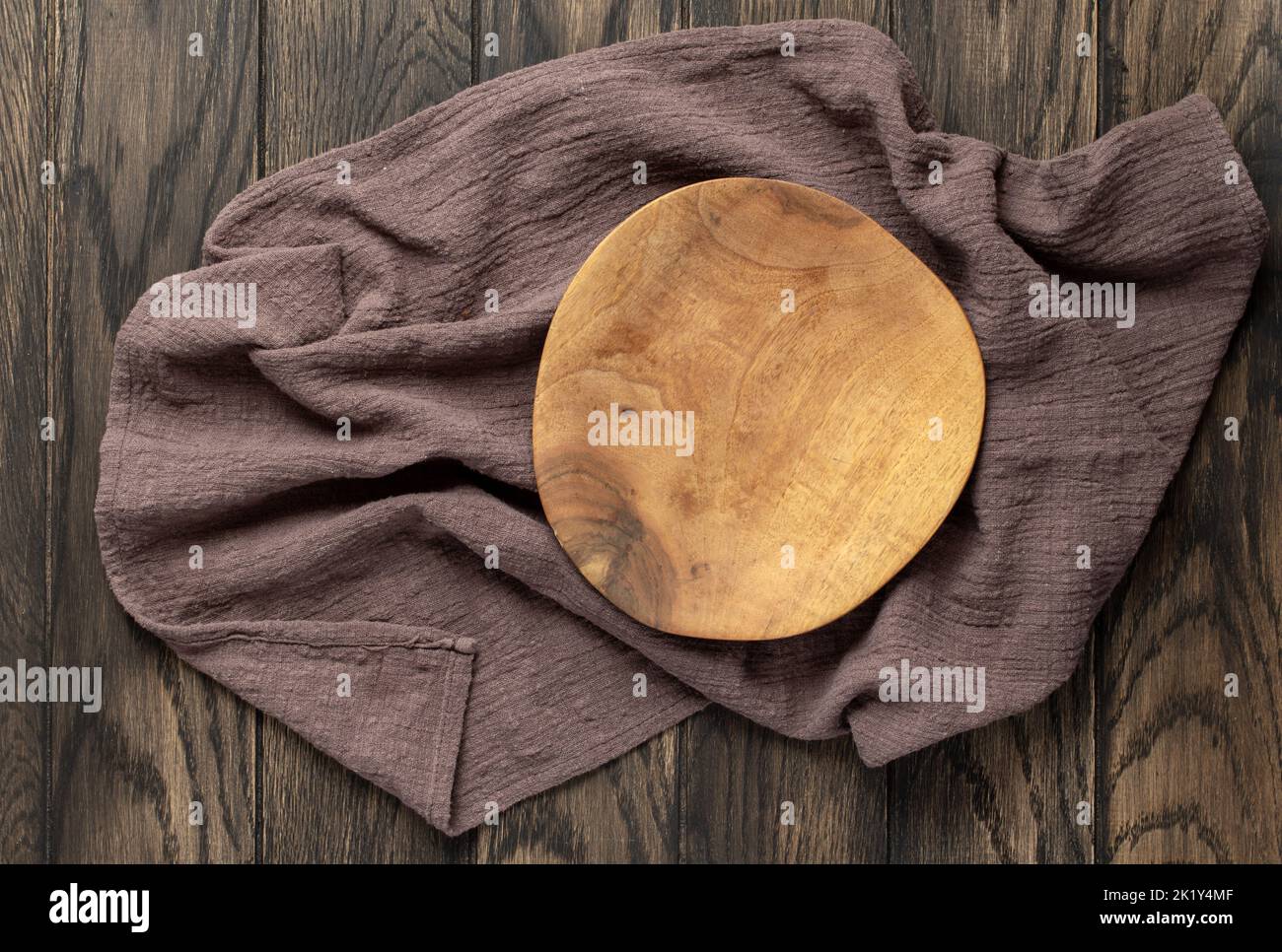 Empty wooden irregular plate on wooden oak kitchen table, top view, flat lay. Food background with copy space Stock Photo