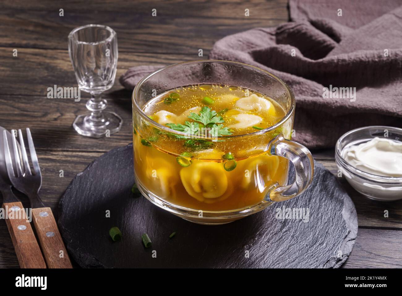 Fresh broth with dumplings in glass bowl on table closeup Stock Photo
