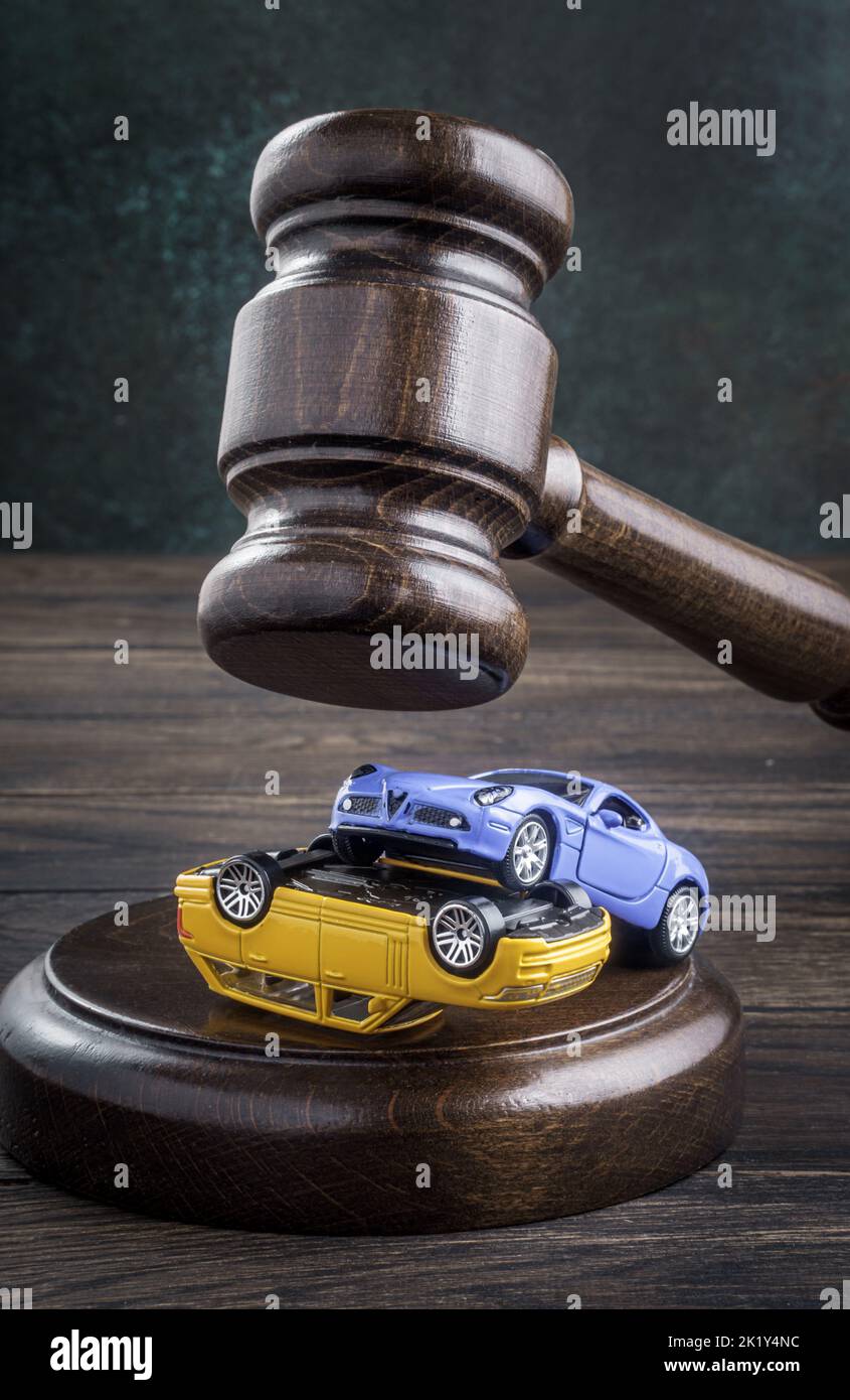 Gavel under collision of two toy cars on wooden table. The concept of legal services, civil court, consideration of an accident case and insurance cov Stock Photo