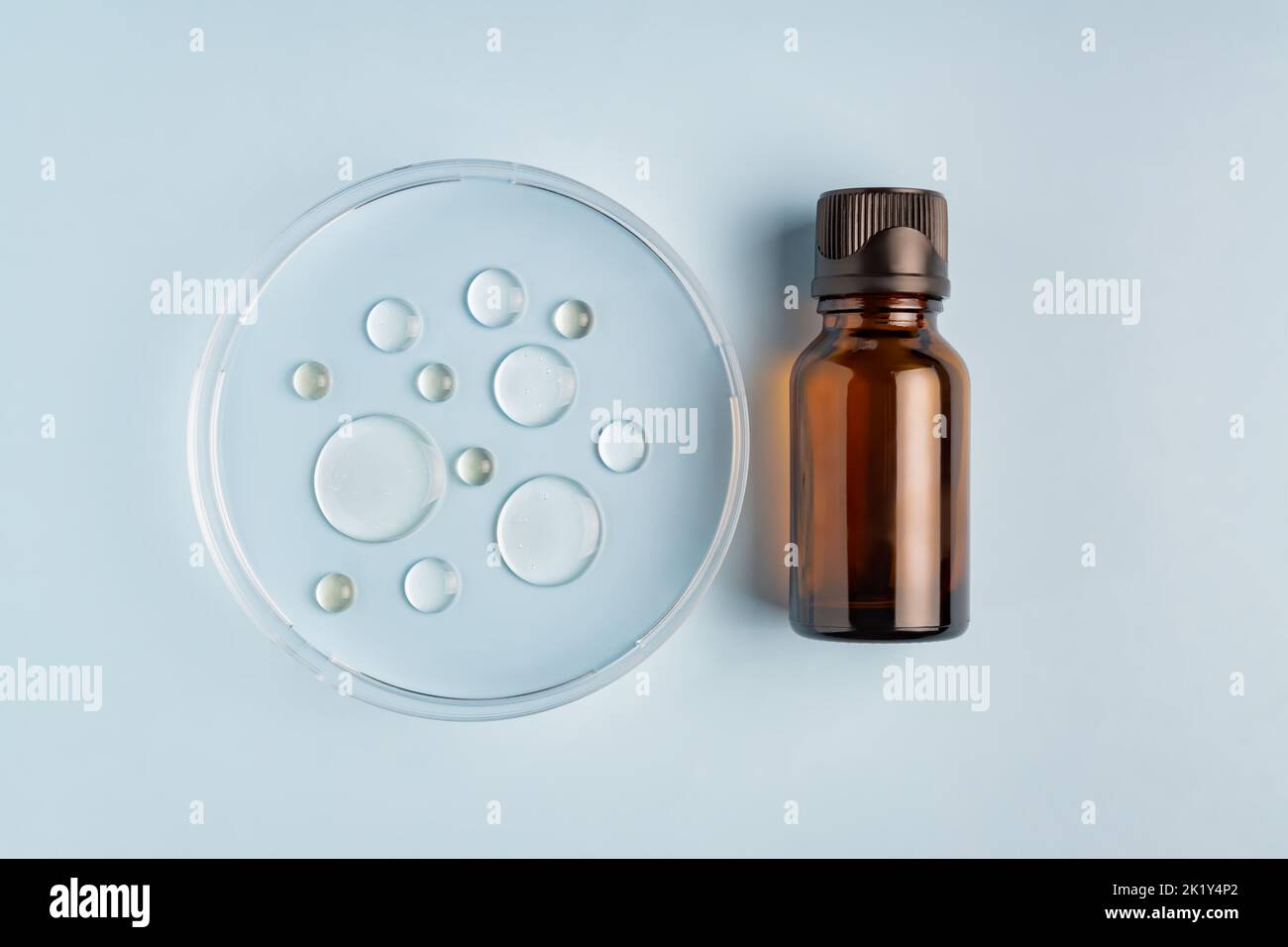 Amber glass bottle. Laboratory glass petri dish with serum, oil, beauty