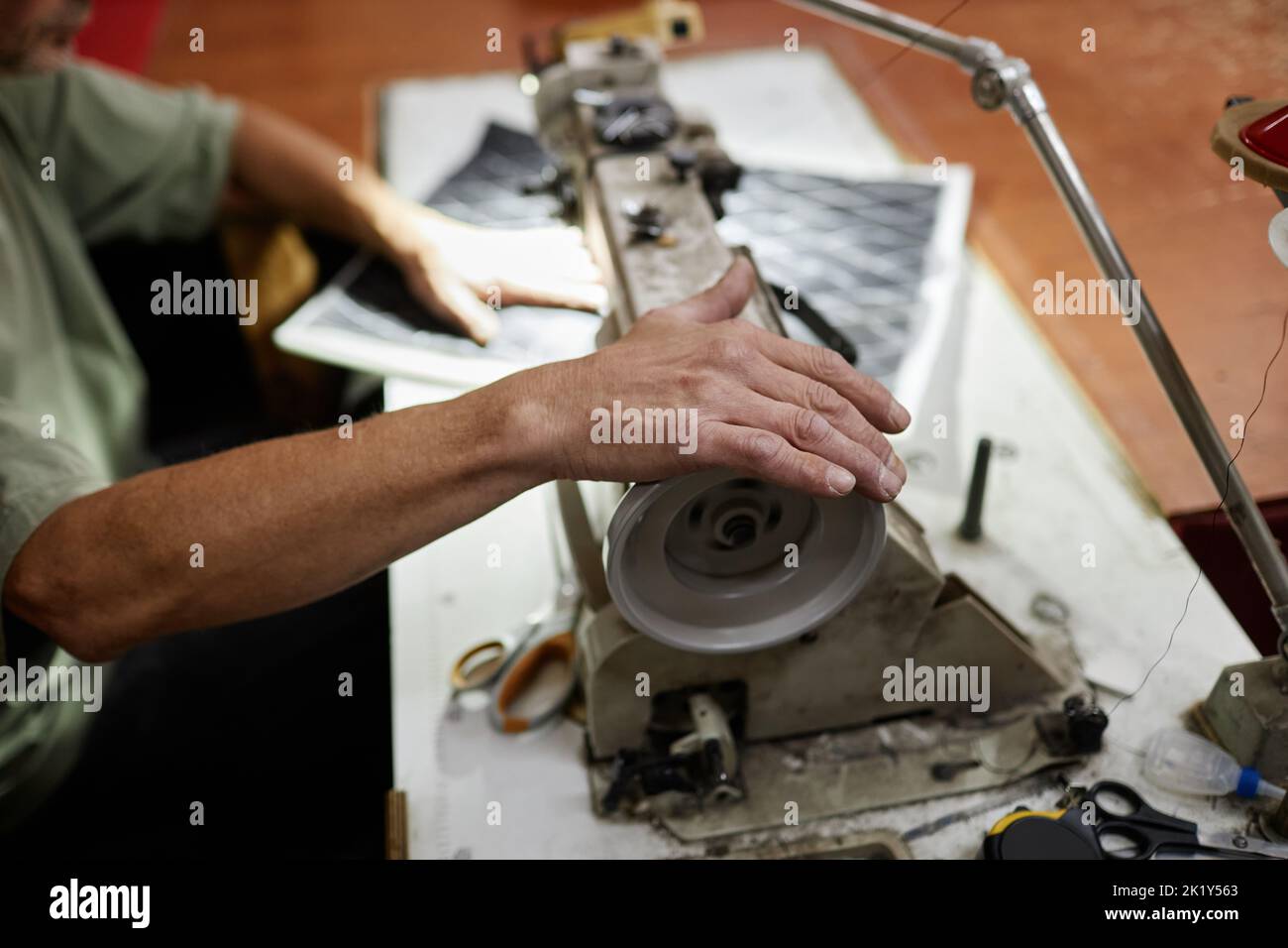 Close up of male worker sewing car upholstery detail with industrial
