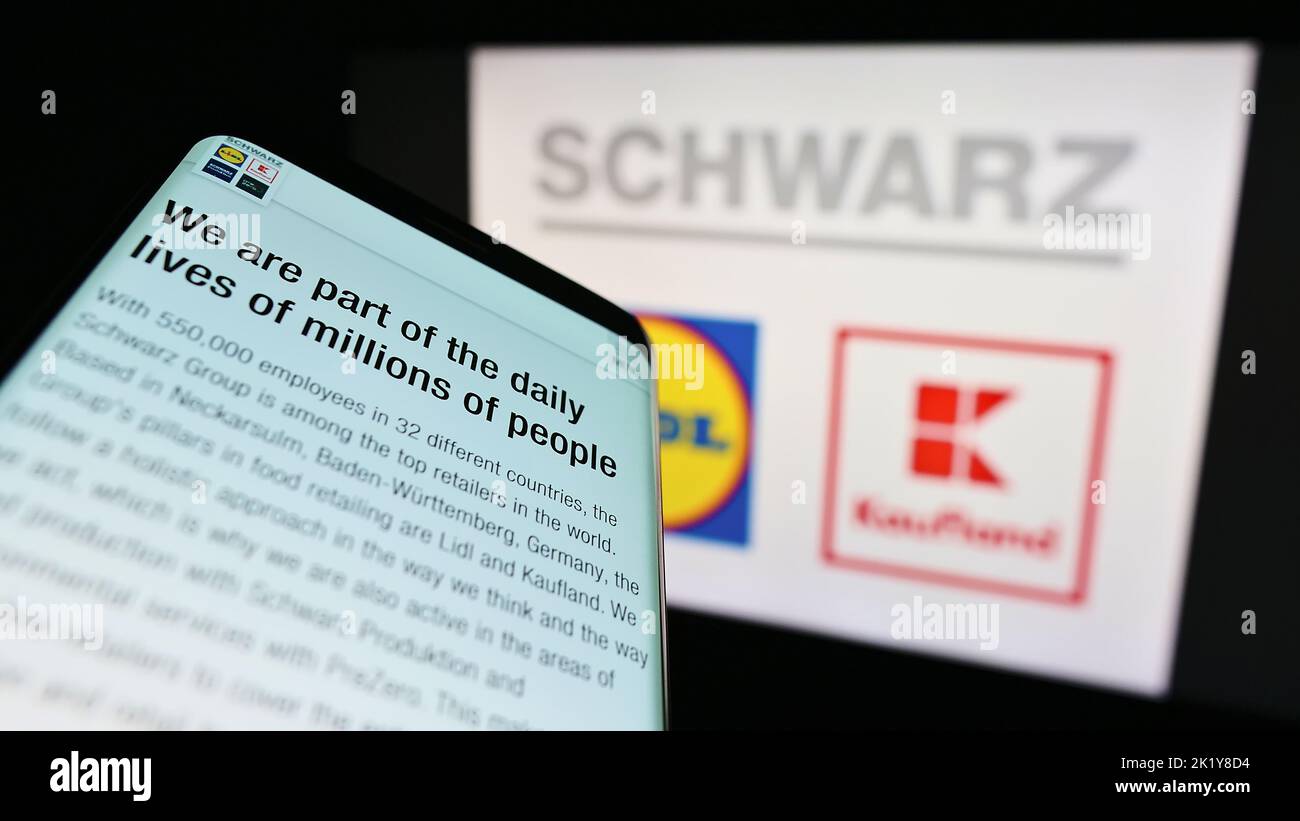 Mobile phone with website of German retail company Schwarz Group on screen in front of business logo. Focus on top-left of phone display. Stock Photo