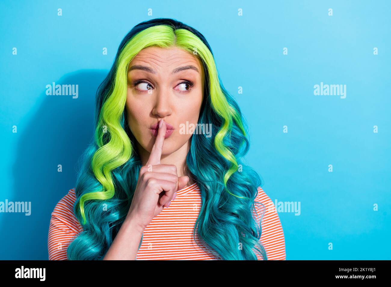 Photo of young charming lady look blank space put finger lips ask to be silent isolated on blue color background Stock Photo