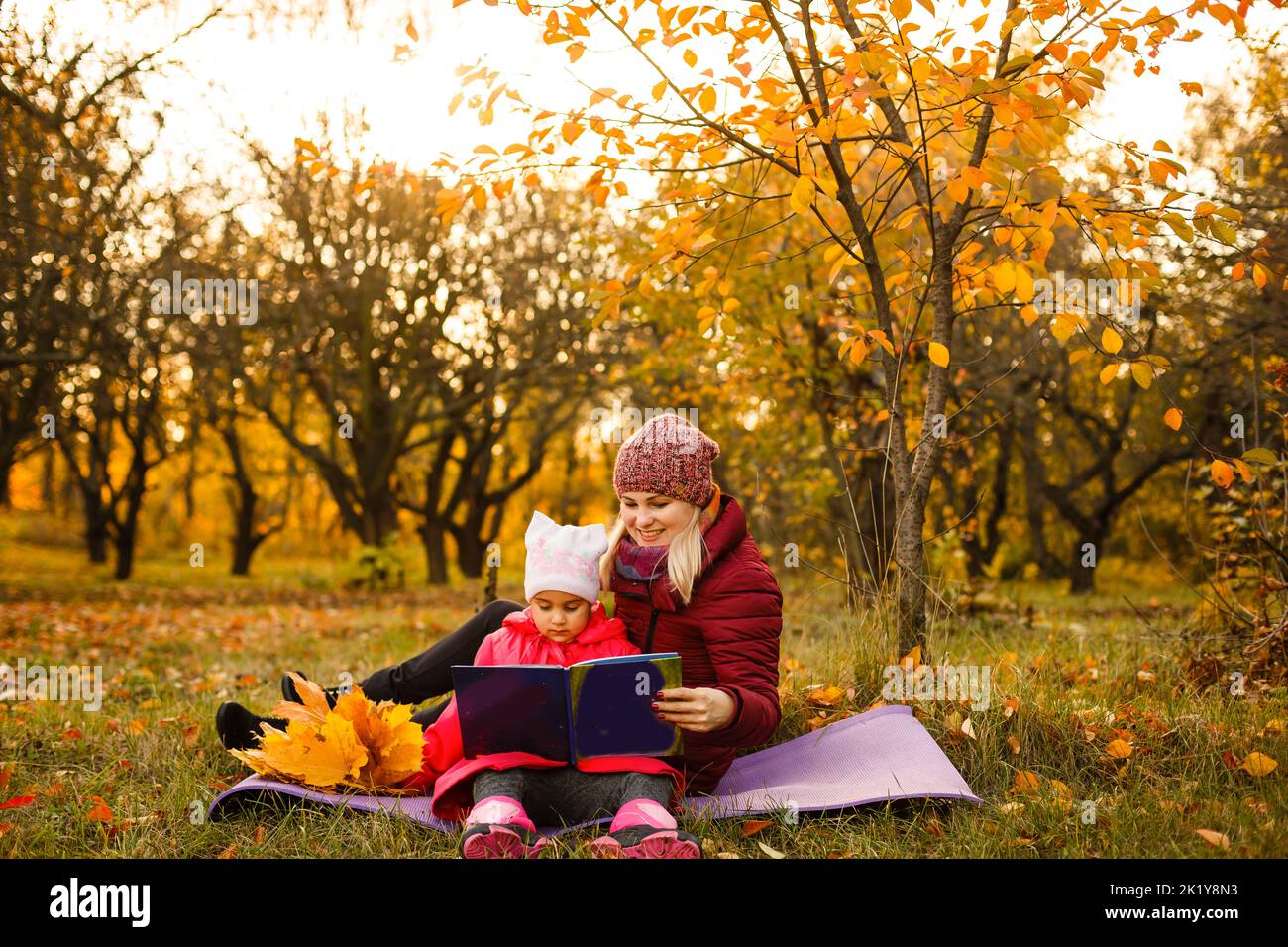 Mother and daughter having fun in the autumn park among the falling ...