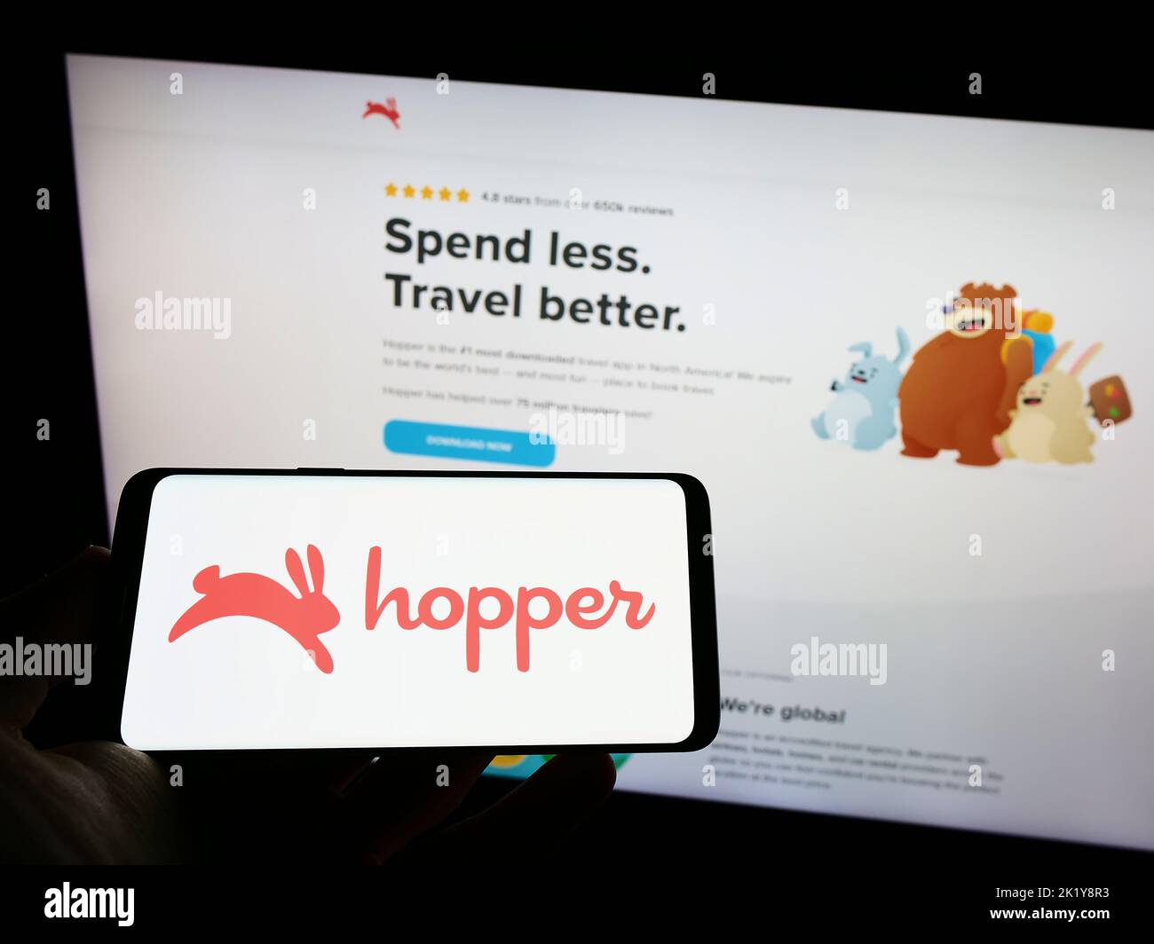Person holding mobile phone with logo of Canadian travel company Hopper Inc. on screen in front of business web page. Focus on phone display. Stock Photo