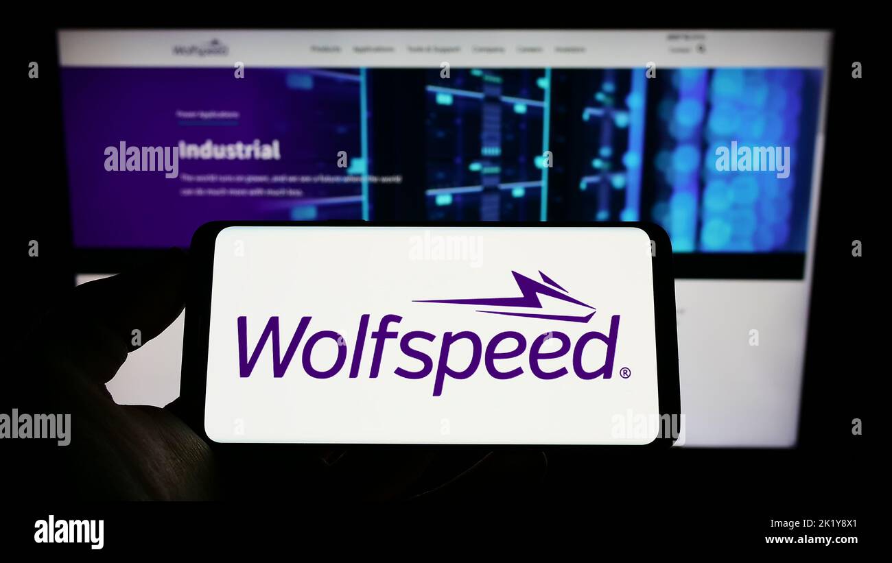 Person holding smartphone with logo of US semiconductor company Wolfspeed Inc. on screen in front of website. Focus on phone display. Stock Photo