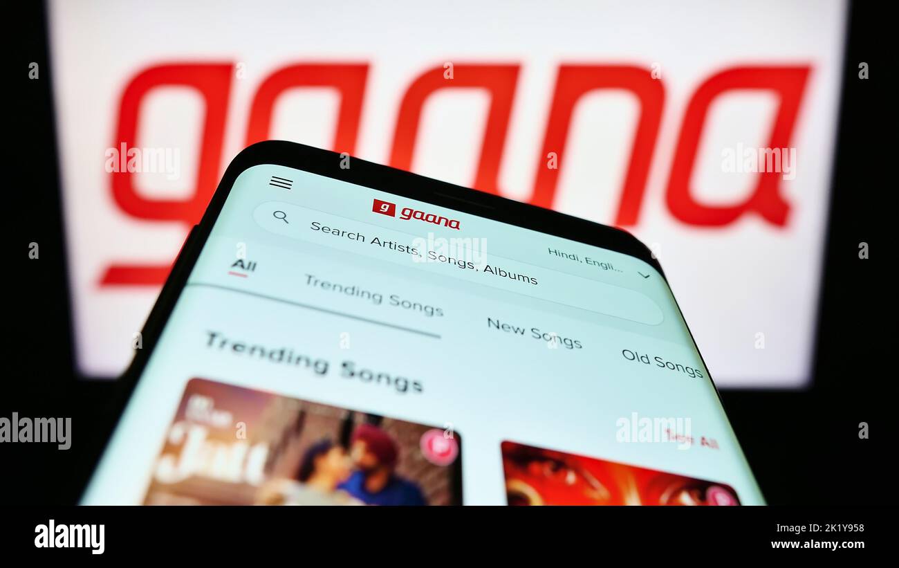 Mobile phone with website of music streaming company Gamma Gaana Ltd. on screen in front of business logo. Focus on top-left of phone display. Stock Photo