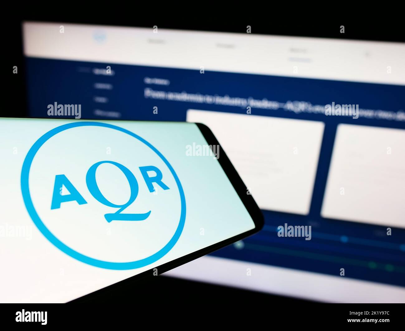 Smartphone with logo of American investment company AQR Capital Management on screen in front of website. Focus on center of phone display. Stock Photo