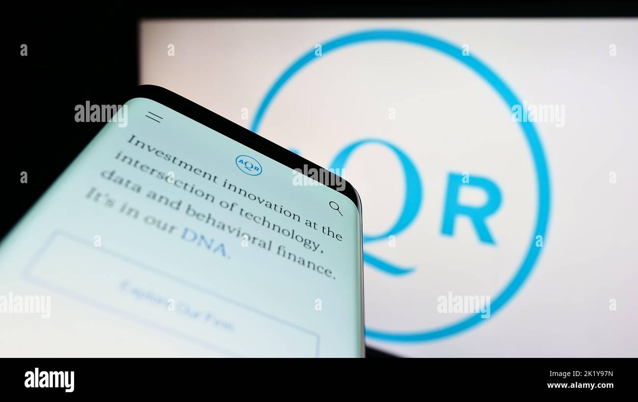 Mobile phone with website of US investment company AQR Capital Management on screen in front of business logo. Focus on top-left of phone display. Stock Photo