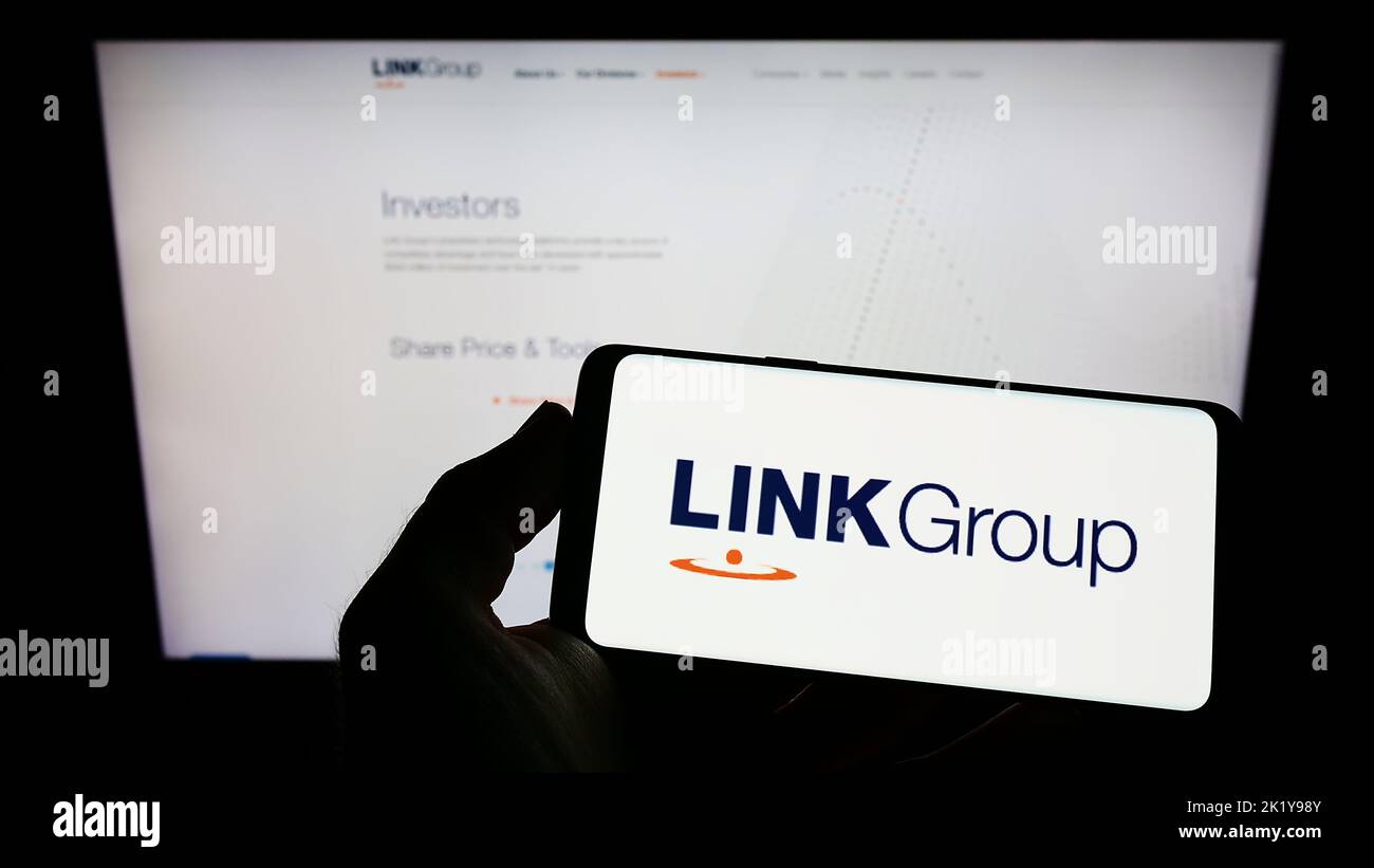 Person holding smartphone with logo of Australian financial company Link Group on screen in front of website. Focus on phone display. Stock Photo