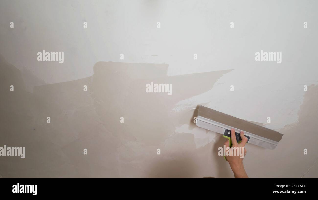 Putty on the concrete wall with a metal trowel. The process of applying