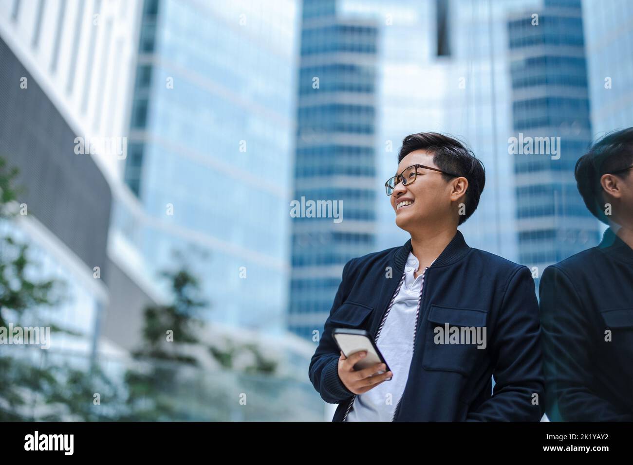 Smiling young businessman using mobile phone in the city Stock Photo