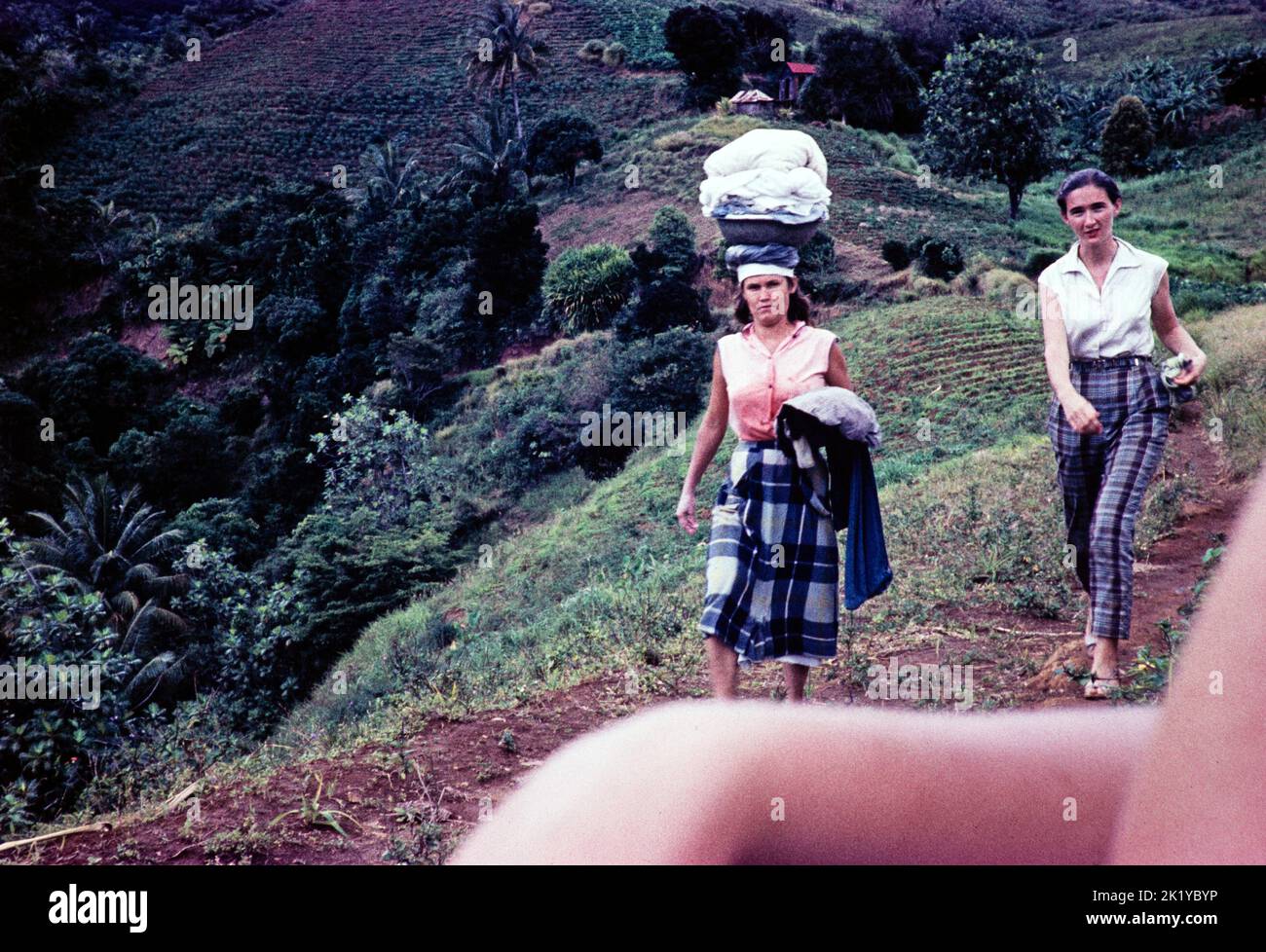 Captioned as 'Poor white farmer's wife carrying washing on her head', Windward Islands, West Indies, 1962 Stock Photo