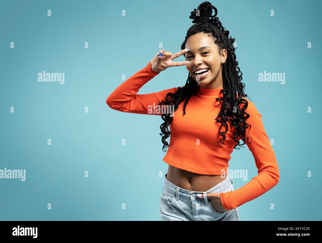 Young smiling friendly positive fun cool cheerful woman 20s showing victory sign isolated on blue backround studio portrait. People lifestyle concept Stock Photo