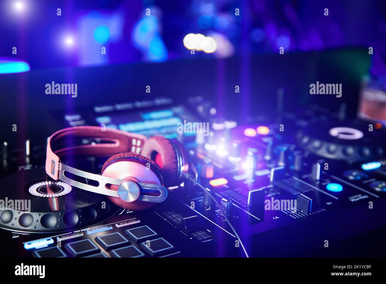 Pink DJ headphones on sound mixer and turntables in night club Stock Photo