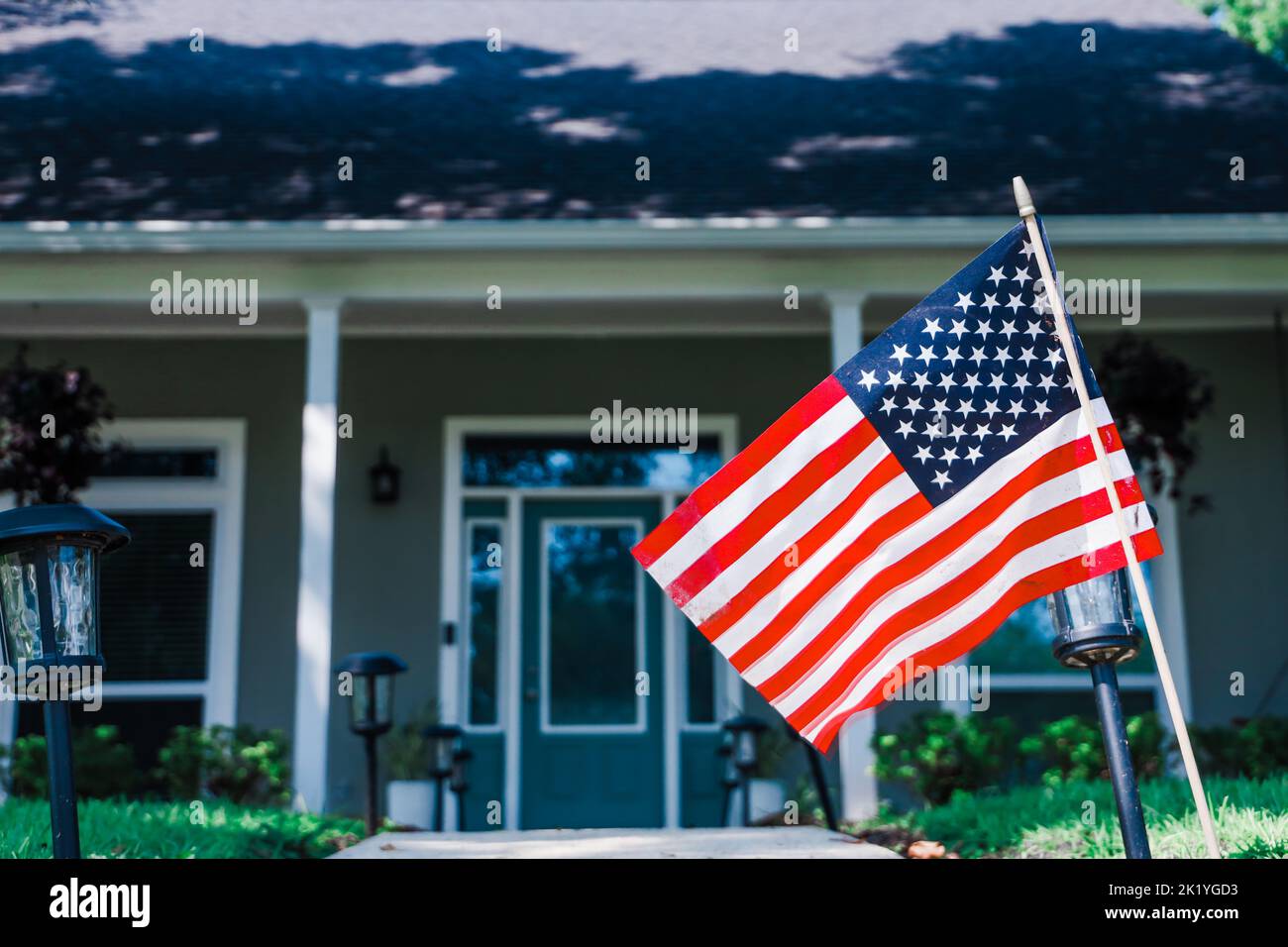 A large American flaghanging outside an Acadian style Louisiana house home. Stock Photo