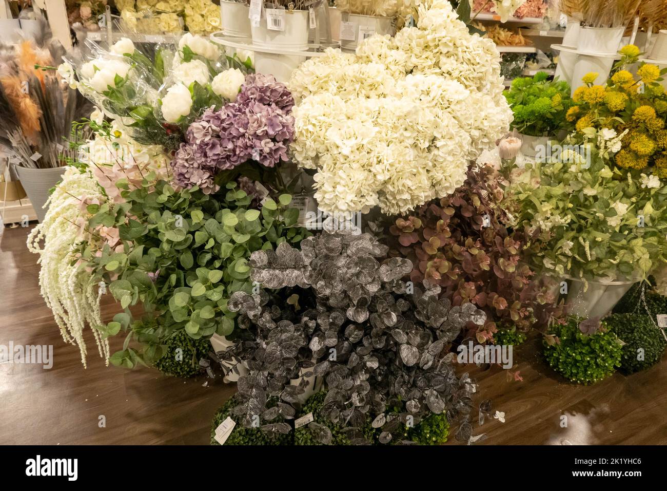 A variety of colourful plastic synthetic flowers in a budget shop in England Stock Photo
