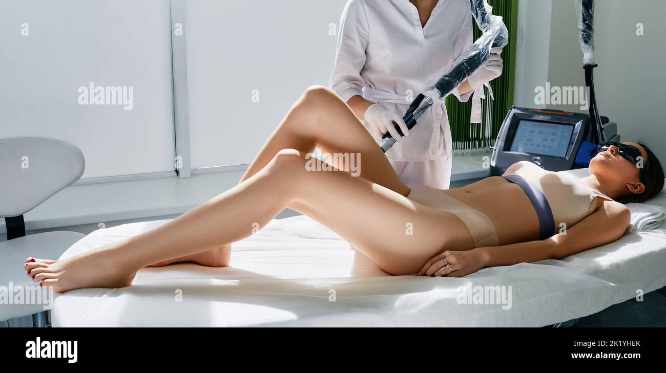 Laser epilation on beautiful female legs at cosmetology clinic with beautician. Legs laser hair removal Stock Photo