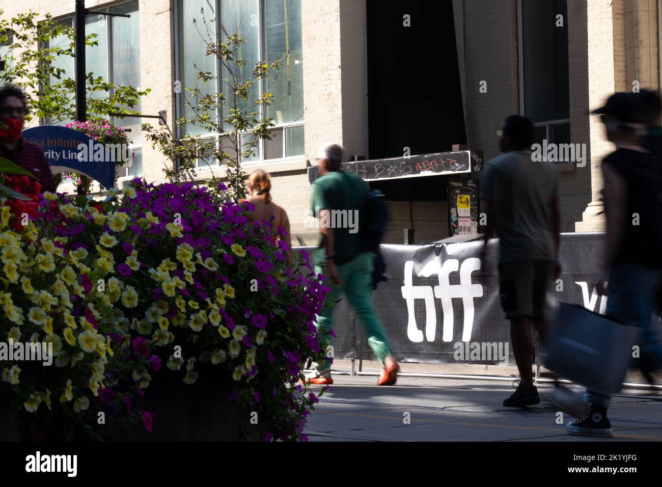 A crowd of people walks by a brightly lit TIFF, Toronto International Film Festival, logo in downtown Toronto during the popular film festival. Stock Photo