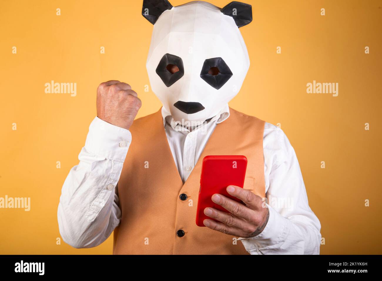 Man in suit and panda mask using a smartphone Stock Photo