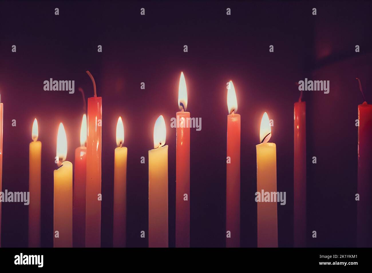 A row of burning candles in the darkness Stock Photo - Alamy