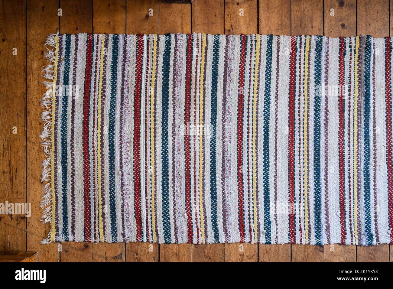 Carpet of multicolored fabrics on an old wooden floor, background textured image. Copy space. Top view. Close-up. Stock Photo