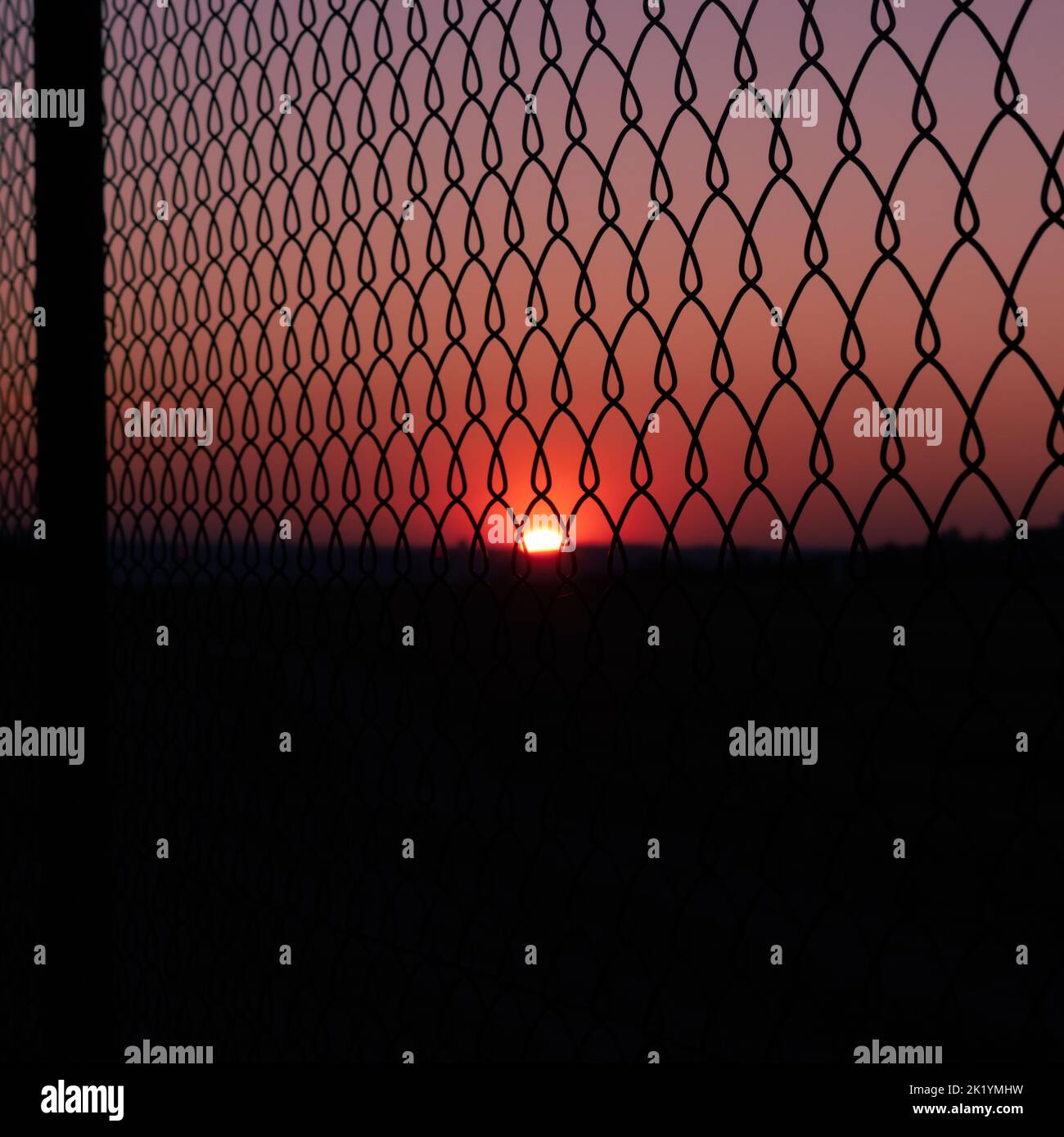 a sunset seen through net of a fence Stock Photo - Alamy