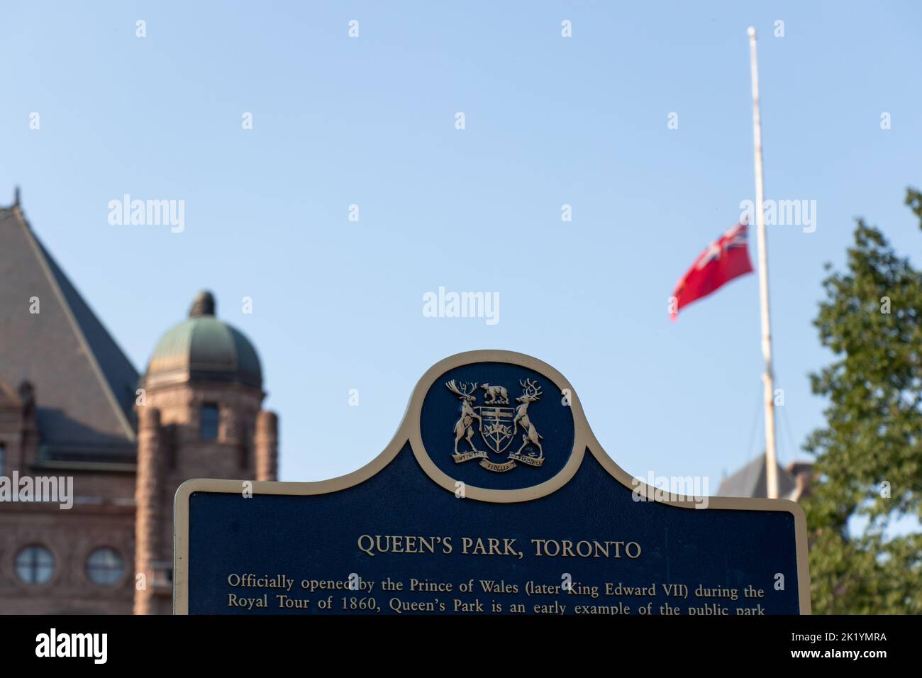 A sign marking Queens Park, the home to the Legislative Assembly of Ontario; seen with the Ontario flag at half staff after death Queen Elizabeth II. Stock Photo