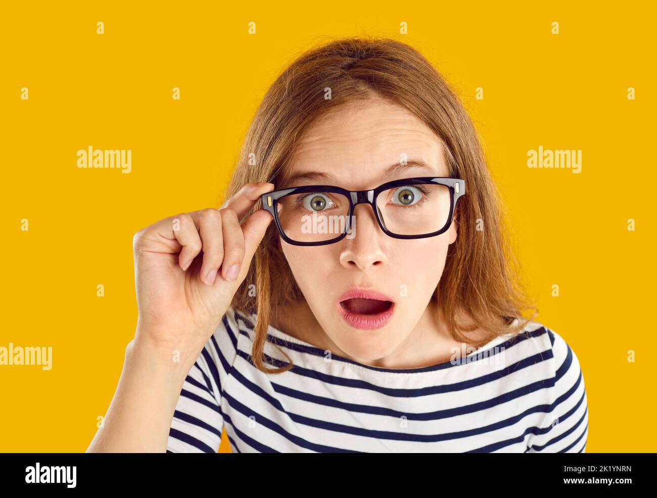 Funny student girl in glasses looking at camera with shocked, astonished face expression Stock Photo