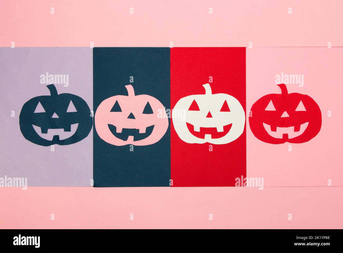 colorful carved pumpkins lined up on colorful background, creative halloween concept, flat lay, paper craft Stock Photo