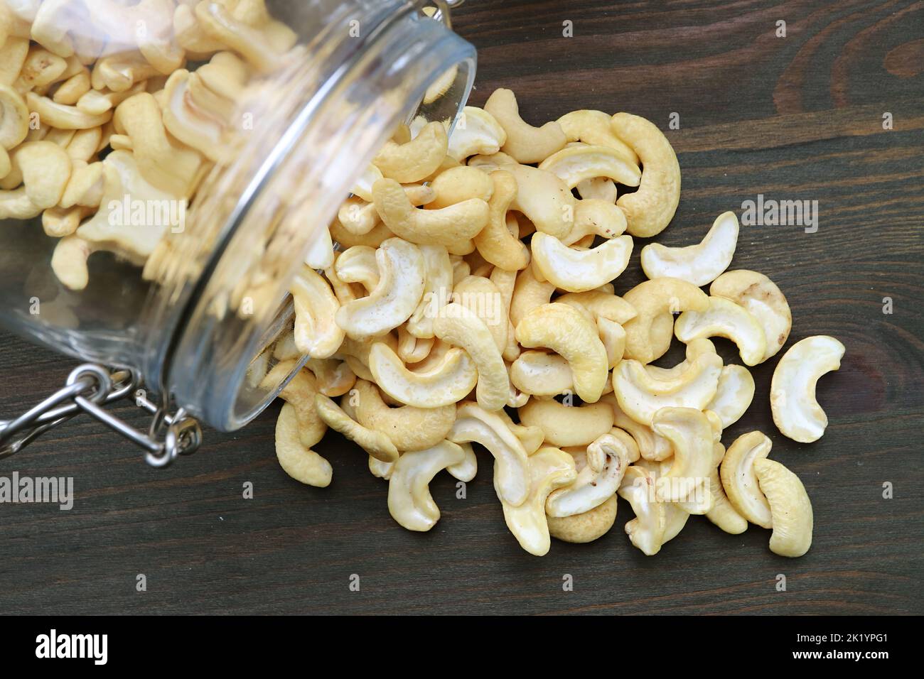 Heap of Casshew Nuts Scattered from a Glass Jar on Wooden Table Stock Photo