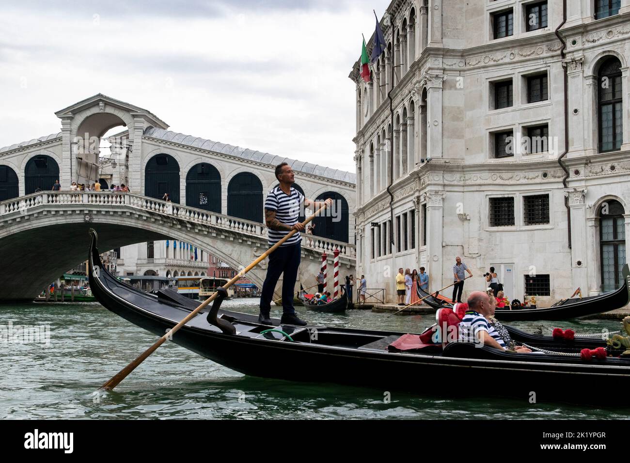 Tourists having a 'gondola' trip accross the channels in Venice, Italy. Rialto bridge on the background Stock Photo