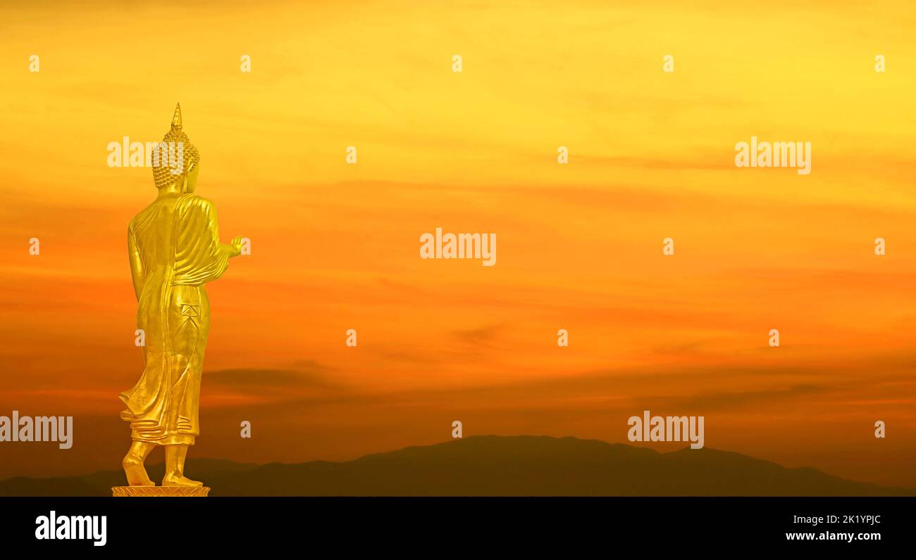 Golden Buddha Image on Gradient Orange Color Sunrise Sky over the Mountains Stock Photo