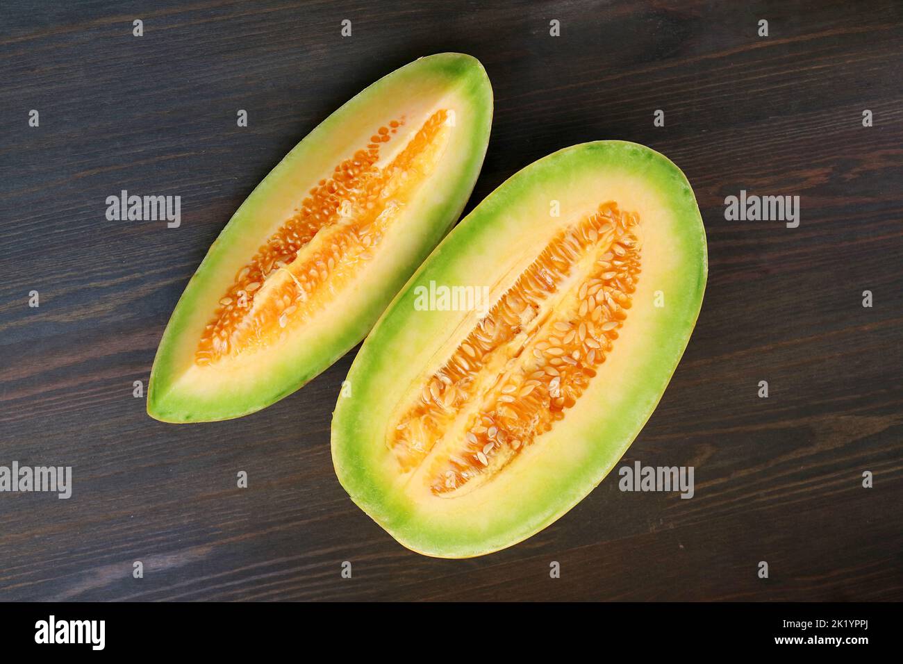 Top View of Slices of Juicy Fresh Ripe Thai Melon on Black Wooden Table Stock Photo