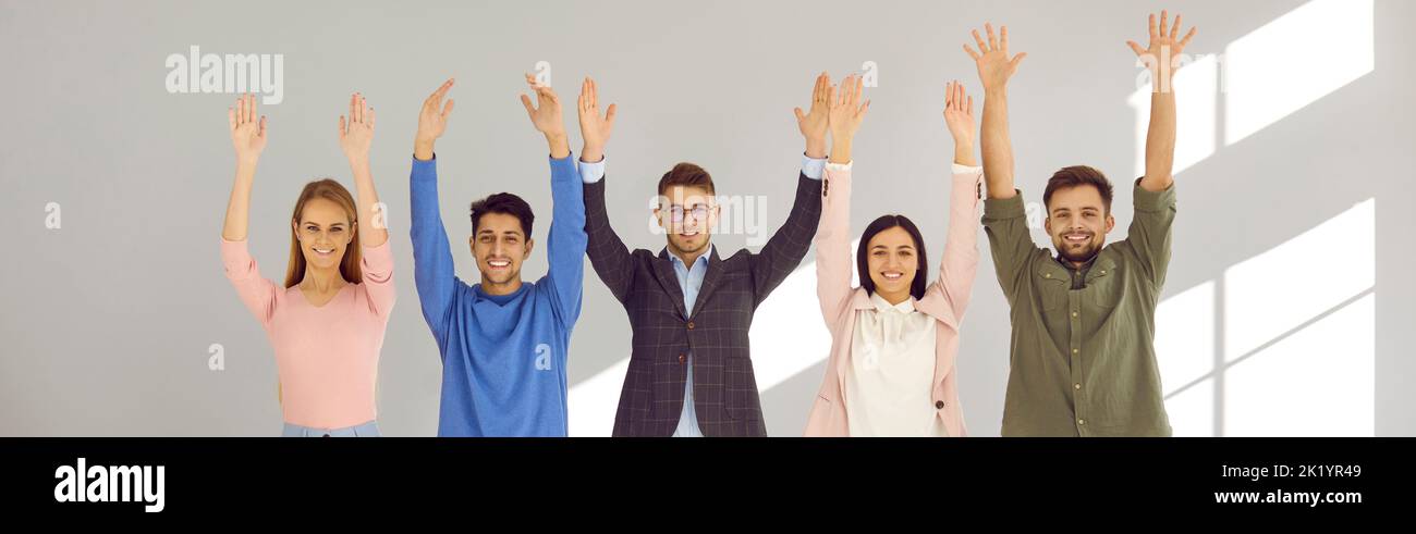 Team of happy young people standing together, raising their hands up ...