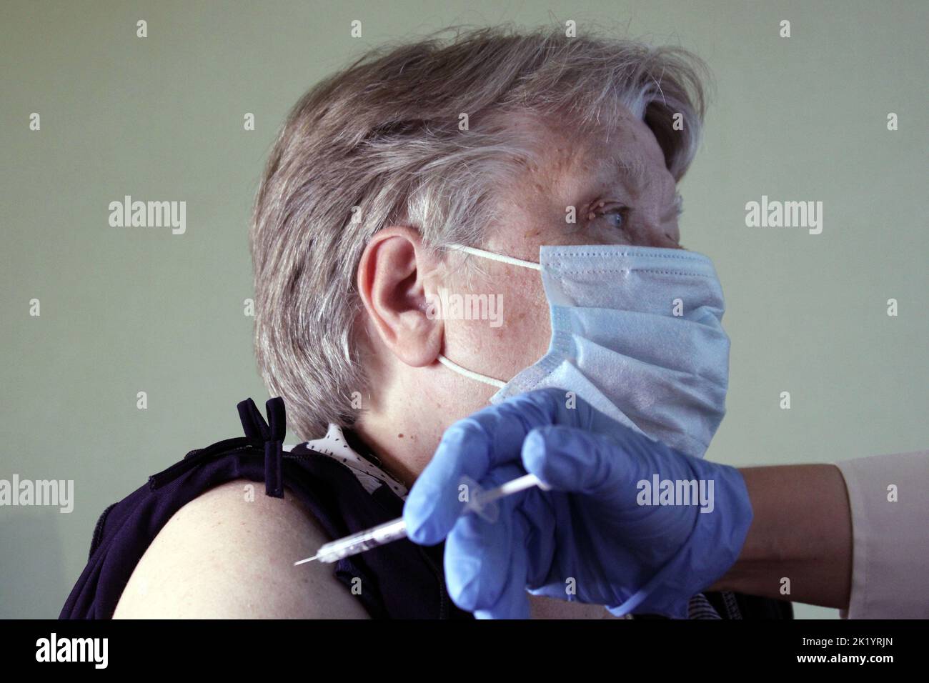 An elderly woman at the doctor's appointment is vaccinated. Syringe with vaccine close-up. The concept of vaccination against Covid19.. Stock Photo