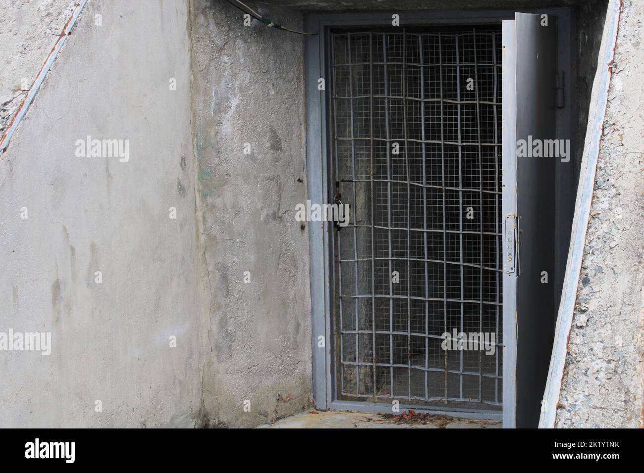 Open door to the cellar with bars in an old stone building. Stock Photo
