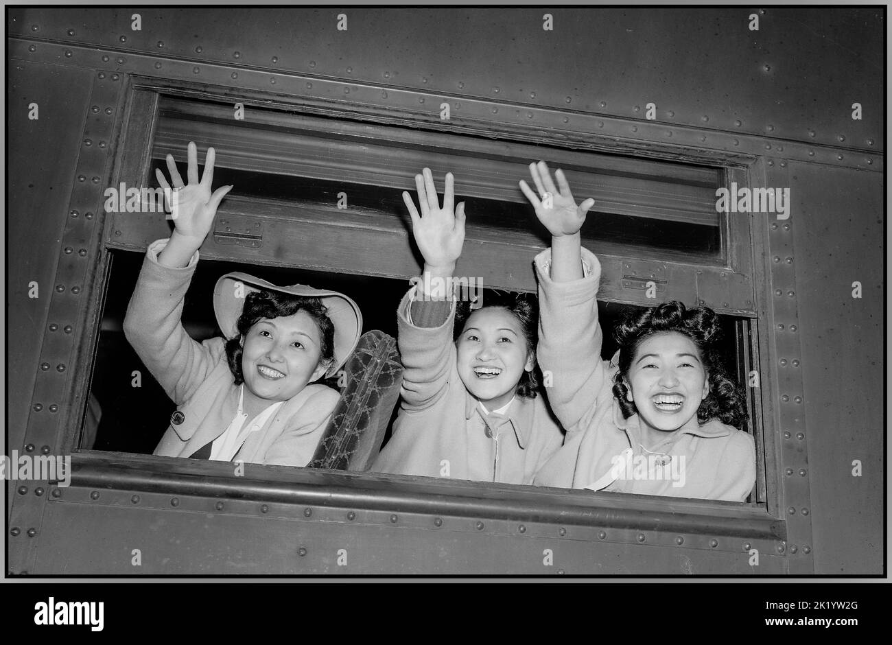 JAPANESE EVACUEES USA WW2 American Propaganda Image of Japanese female citizens being relocated to a processing center. Los Angeles, California. Waving good-bye as the train pulls away from the station. These girls are on their way to an assembly center with others from this area of Japanese ancestry. They will later be transferred to a War Relocation Authority center to spend the duration. Date 1 April 1942 World War II Second World War Pacific War Stock Photo