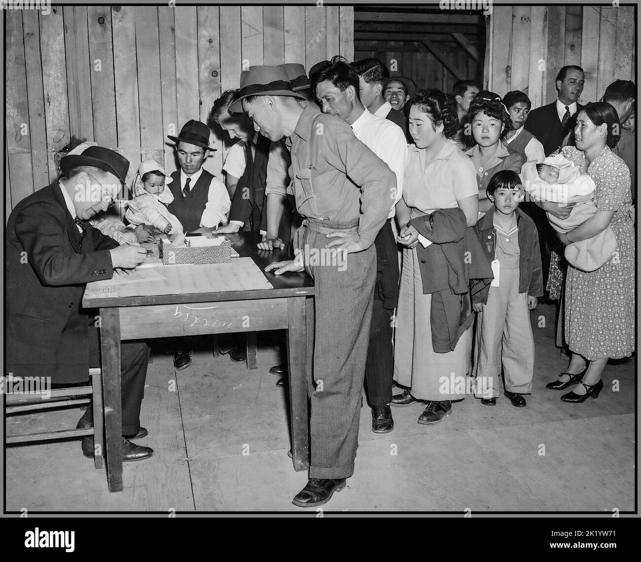 WW2 Japanese citizens relocating in the USA Arcadia, California. Attendants register arrivals at Santa Anita assembly center and assign them family by family, to new quarters. The family unit is kept intact. These evacuees of Japanese ancestry are transferred later to War Relocation Authority centers for the duration. Date5 April 1942 Stock Photo
