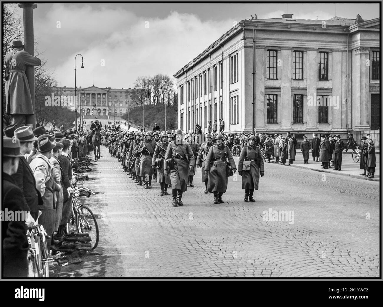 WW2 Nazi Germany occupation in Oslo Norway 1940-04-09 Wehrmacht soldiers marching Karl Johans gate Slottet. People watching with mounted police World War II Nazi occupation Oslo Norway 1940 Troops of the Wehrmacht, the military forces of Nazi Germany, in Oslo, Norway on April 9, 1940, the first day of the German invasion and occupation of Norway in World War II. The soldiers are equipped with greatcoats, jack boots, steel helmets, MP 40 sub machine guns,etc Oslo Norway Stock Photo