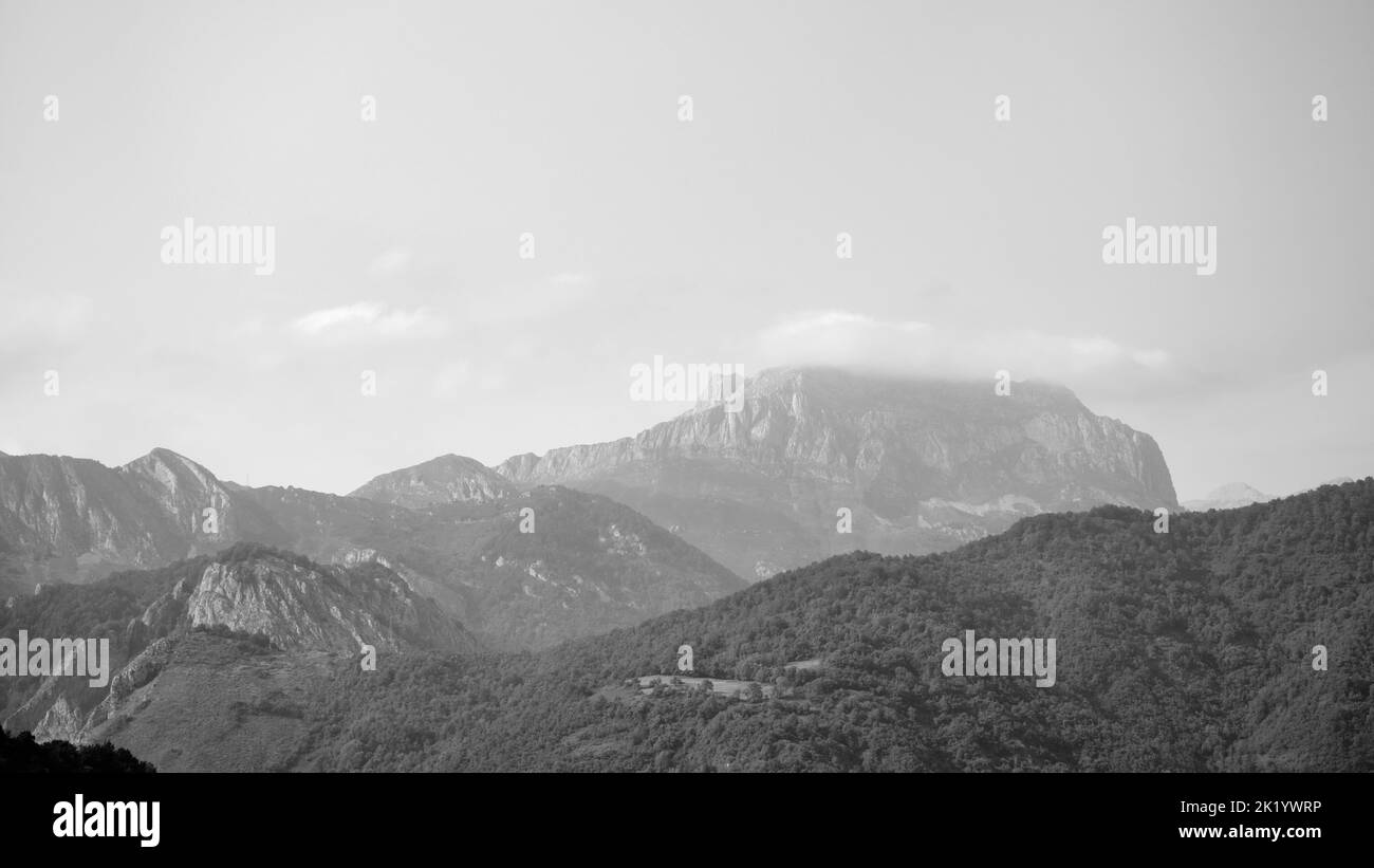Black and white image of the Picos de Europa (Peaks of Europe), a mountain range in northern Spain, at dusk. Mountain peak is covered by clouds. Stock Photo
