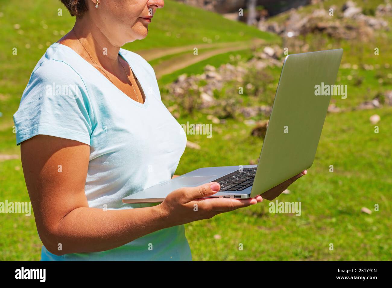 The girl works on a laptop in the mountains. Freelance work Stock Photo